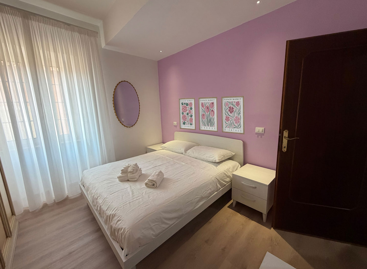 Camera matrimoniale elegante con parete rosa e ampia finestra nella Casa Vacanze Antea
